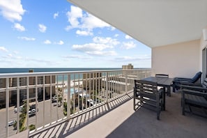 A balcony with a view of the ocean and a pool area.