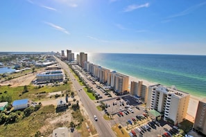 A coastal hotel with multiple high-rise buildings, a parking lot, and a beach view.