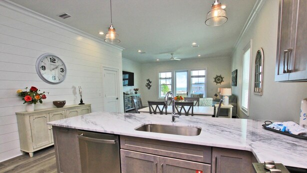 A kitchen with a large island, stainless steel appliances, and a clock on the wall.