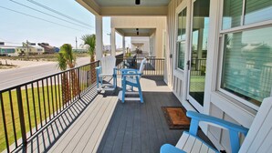 A covered porch with a railing, a table, and two chairs.