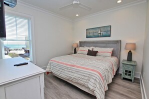 Un dormitorio con cama, mesitas de noche, un cuadro y una ventana con persianas.