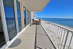 A balcony with a view of the beach, a table with chairs, and a railing. - San Carlos 801 (Gulf Shores)