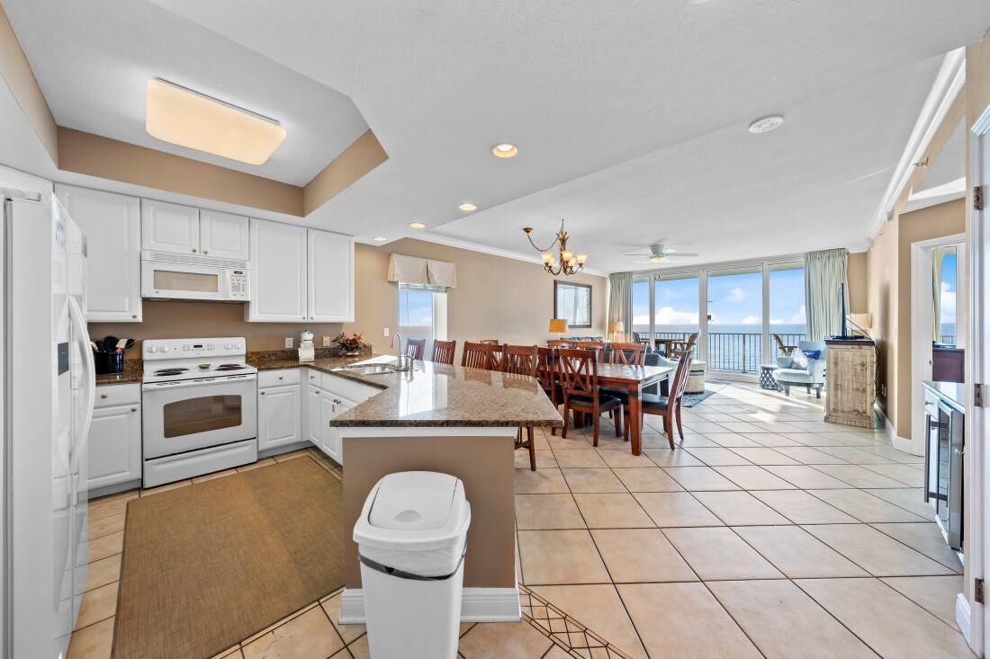 A spacious kitchen with white cabinets, a granite countertop, and a large island.