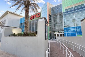 A modern building with a prominent 'AMC' sign, large glass windows, and a palm tree in front. - The Wharf 902 by Youngs Suncoast (Orange Beach)