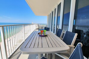 A balcony with a table and chairs, overlooking a beach and cityscape.