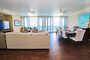 Relax in this stylish living area with a sofa, armchairs, and dining table, offering a balcony with ocean views.