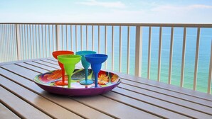A table with colorful glassware on a balcony overlooking the sea. - San Carlos Penthouse 5 (Gulf Shores)