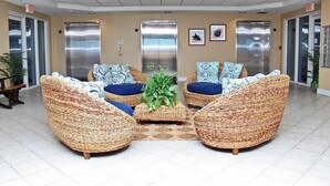 A lobby with wicker furniture, two elevators, and a plant centerpiece. - San Carlos Penthouse 5 (Gulf Shores)