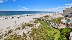 A beach with a wooden walkway leading to a building with a pool. - San Carlos 409 (Gulf Shores)