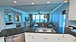A modern kitchen with a central island, a dining area with a view, and a large window overlooking the ocean. - San Carlos 409 (Gulf Shores)