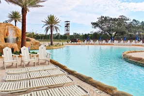 A pool area with lounge chairs and a palm tree. - The Wharf 521 by Youngs Suncoast (Orange Beach)
