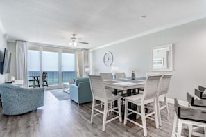 A spacious living area with a dining table, chairs, a sofa, and a balcony with a view. - San Carlos 808 (Gulf Shores)