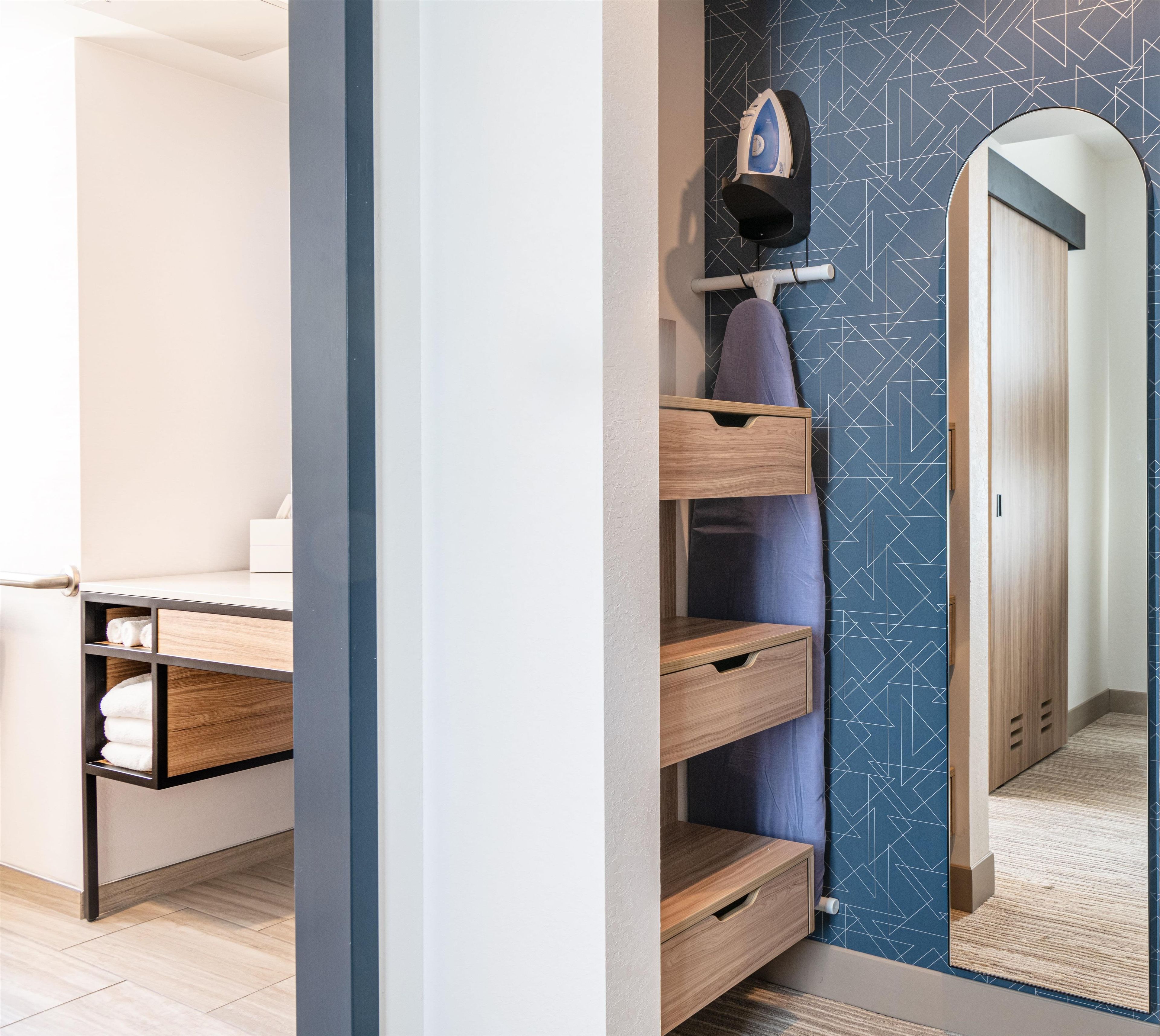 Une chambre d’hôtel avec un lit, un bureau en bois, une armoire et un miroir.