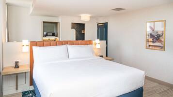 Een hotelkamer met een bed, nachtkastjes, een magnetron, een tv aan de muur en een ingelijste foto.