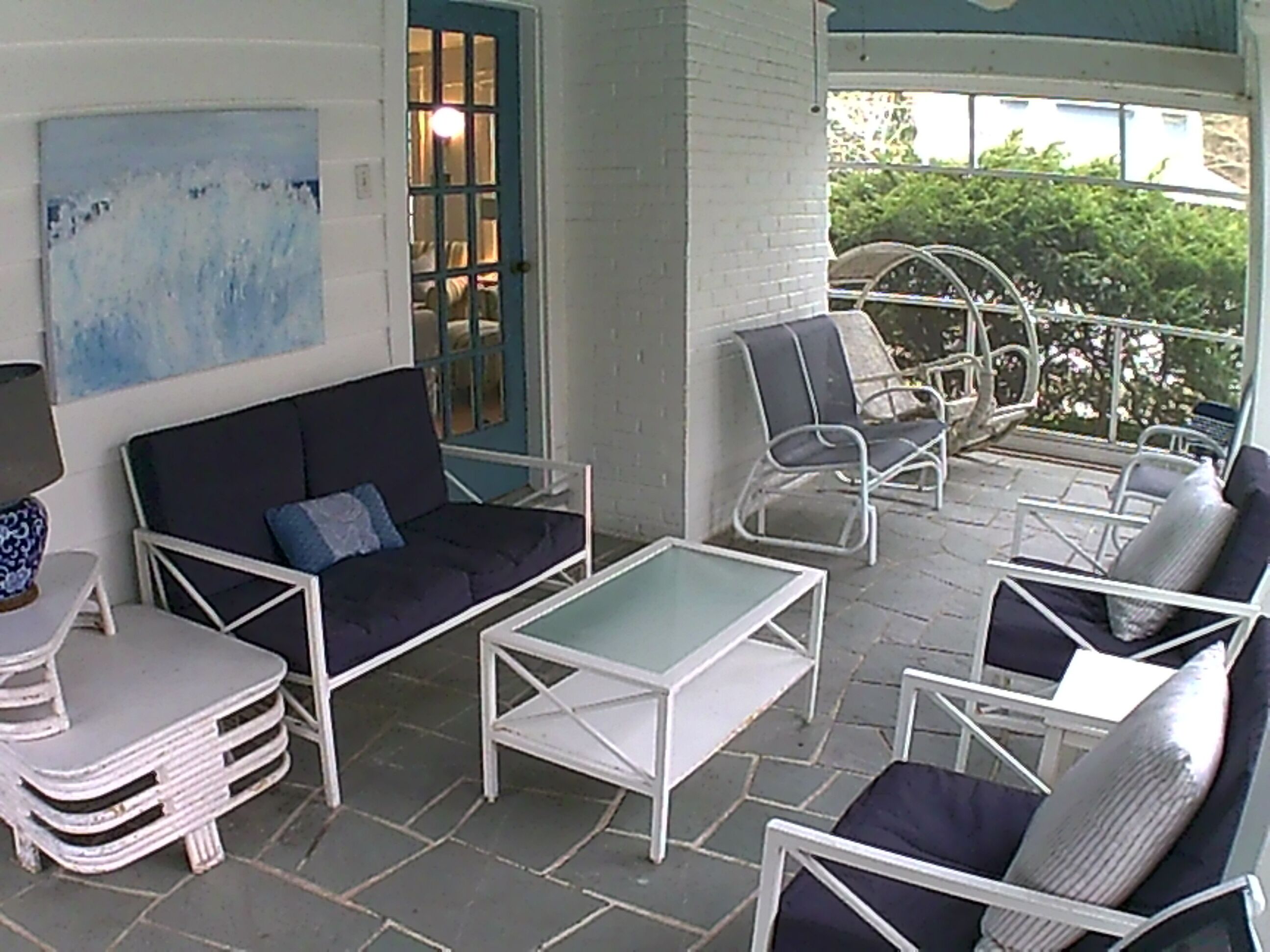A covered outdoor seating area with a sofa, chairs, and a table.