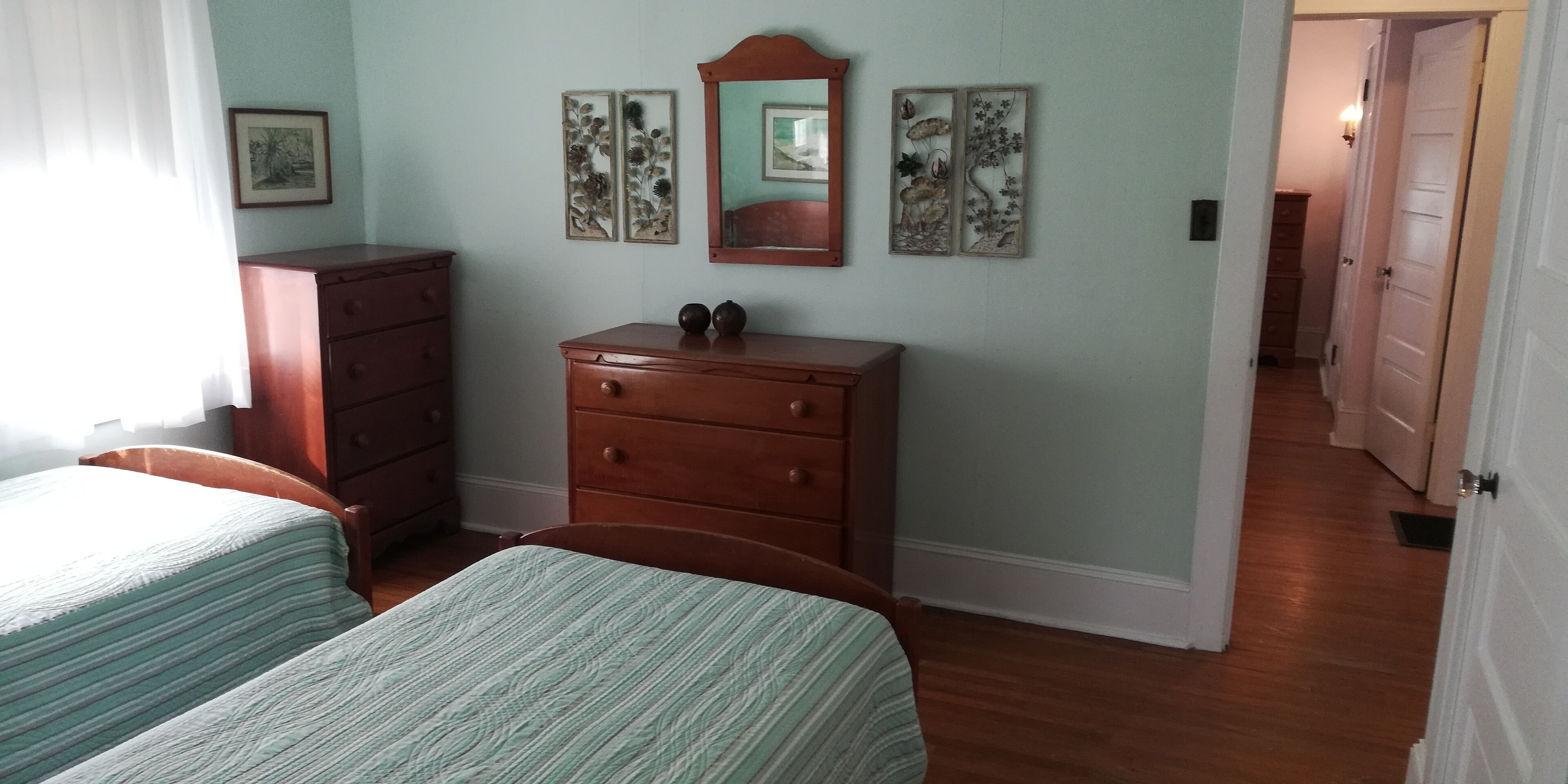 A bedroom with two beds, a dresser, and a mirror on the wall.