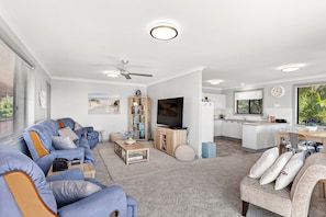 A modern living room with a sofa, television, and a dining area with a kitchen in the background. - Wahgunyah Family Friendly in Nelson Bay (Nelson Bay)