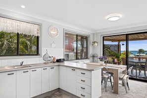 A modern kitchen with white cabinets, a built-in island, and a view of the outdoors. - Wahgunyah Family Friendly in Nelson Bay (Nelson Bay)