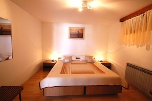 Een slaapkamer met een groot bed, nachtkastjes, een spiegel en een schilderij aan de muur.