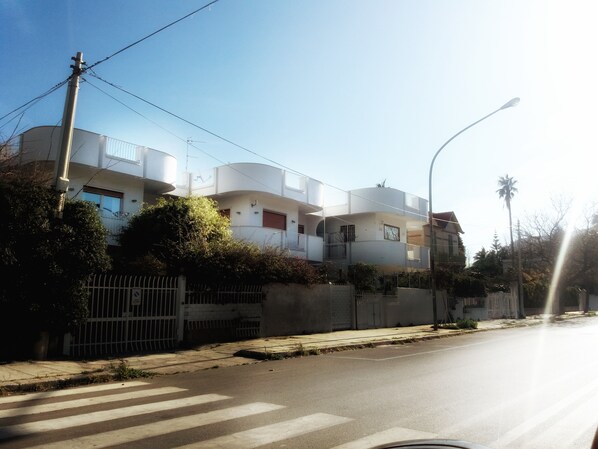 Ein mehrstöckiges Wohnhaus mit Balkonen, einem verschlossenen Eingangsbereich und blauem Himmel.