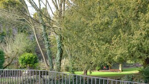 A park with a paved walkway, benches, and a stone wall.