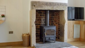 A room with a stone fireplace, a television, and a wicker basket.