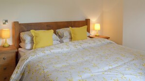 A neatly made bed with floral bedding, two bedside lamps, and a wooden nightstand with drawers.