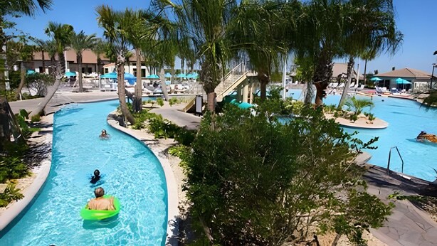 Un complexe hôtelier doté de plusieurs piscines, de palmiers et d’espaces de détente.