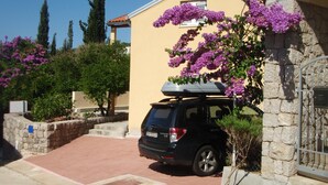 Un SUV negro estacionado en una entrada con un muro de piedra y una verja.