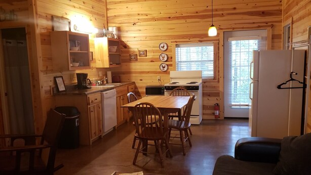 Une cuisine chaleureuse, aménagée dans le style d’un chalet, avec des murs en bois et un coin repas.