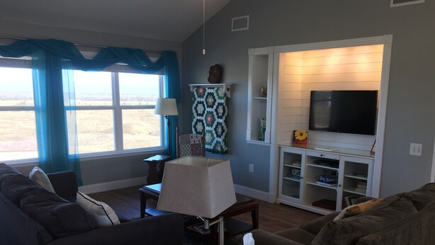 A living room with a sofa, a coffee table, a lamp, a TV, and a bookshelf. - Our Cozy, Quiet, Comfortable place in the Country - 2 Bedroom 900 sq ft w/view (Lockhart)