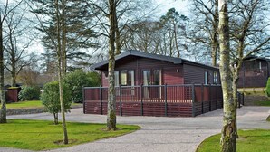 A wooden cabin with a porch and a gravel driveway. - 2 bedroom accommodation in Burnside Park (Burnside Park)