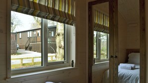 A room with a bed, a window with a view of a wooden deck and a house, and a mirror reflecting the bed. - 2 bedroom accommodation in Burnside Park (Burnside Park)