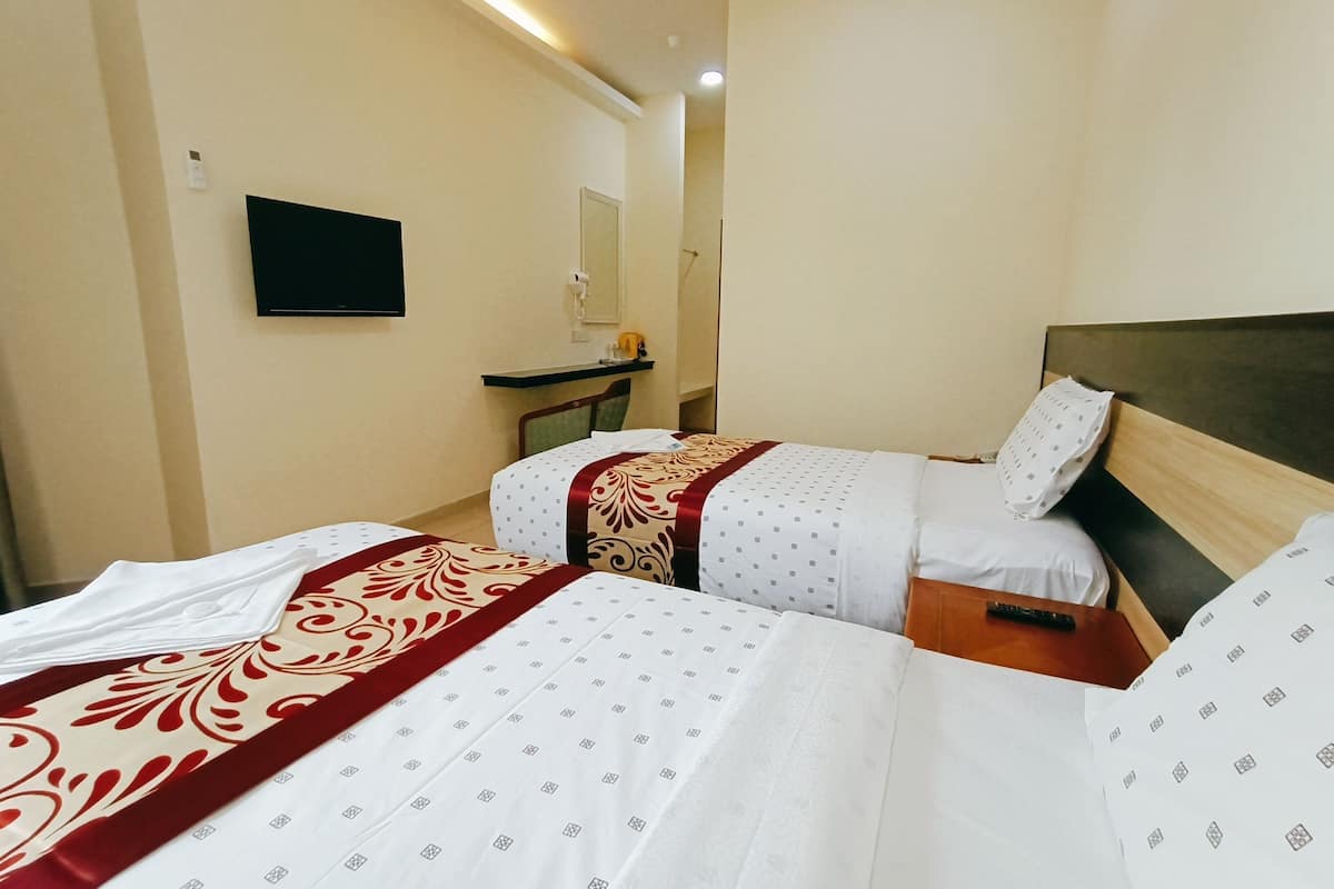 Een hotelkamer met twee bedden, een televisie aan de muur en een klein bureau met een spiegel.
