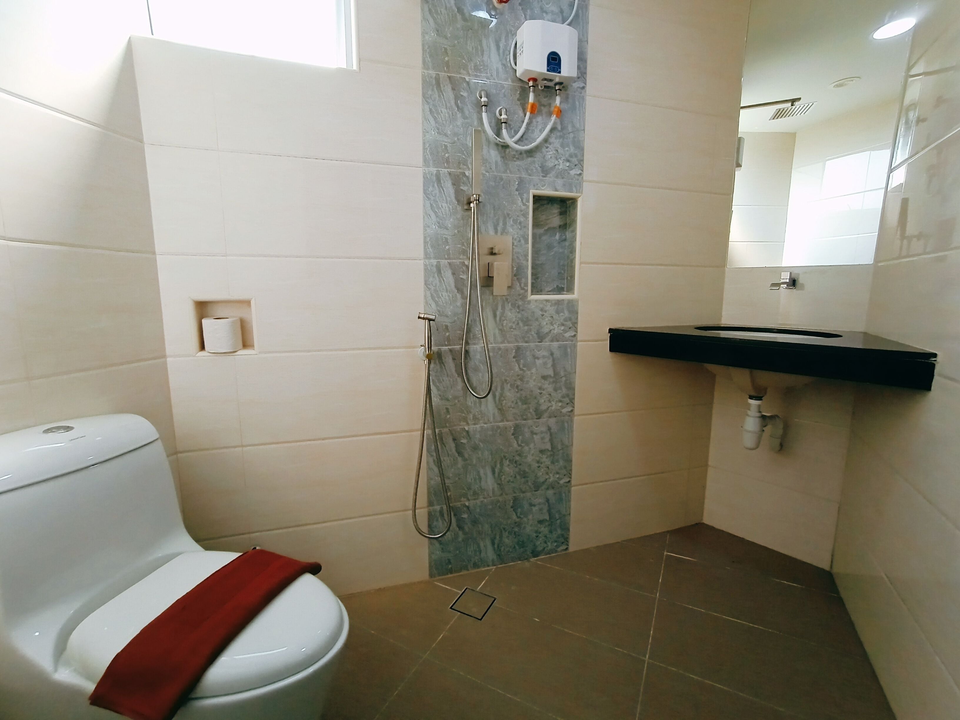 A bathroom with a toilet, a shower, a sink, and a marble wall.