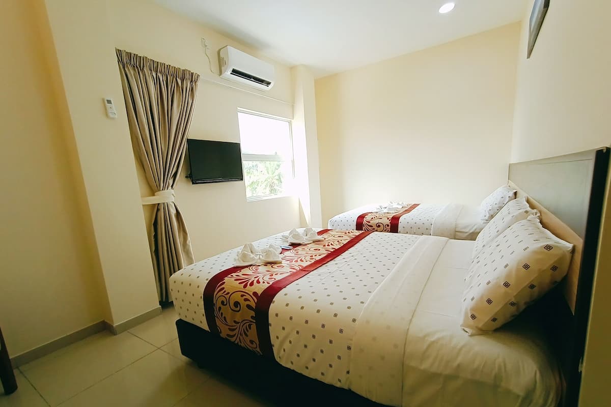 Een hotelkamer met een bed, gordijnen, een airconditioning, een televisietoestel en een raam.