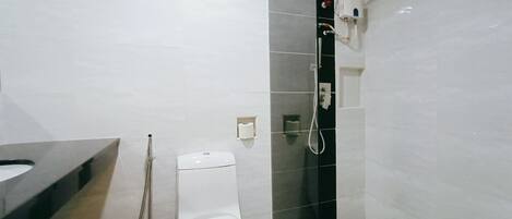 A modern bathroom with a toilet, a shower, and a sink.