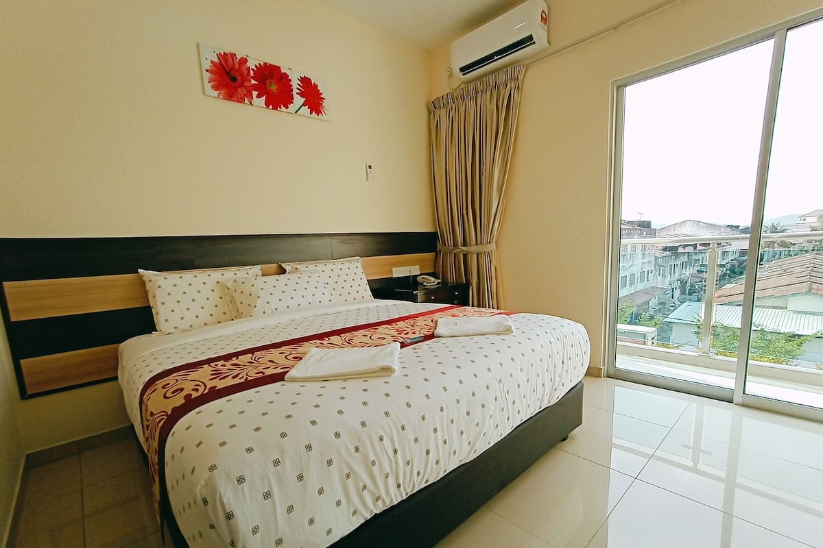 Hotelkamer met een groot bed, hoofdeinde, nachtkastje, airconditioning en een raam met gordijnen, met uitzicht op de stad.