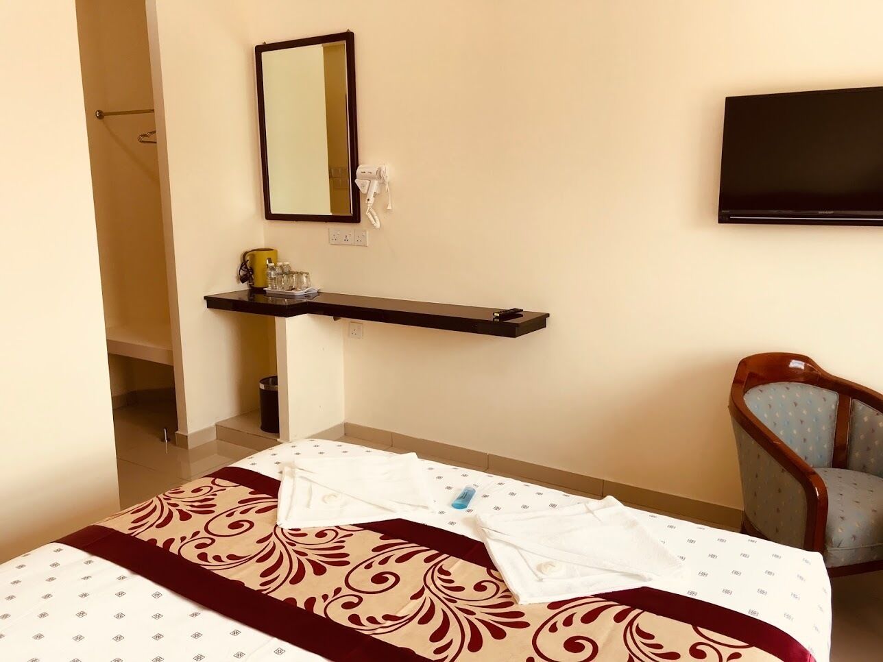 Ein Hotelzimmer mit Bett, Sessel, Ablagefläche für Toilettenartikel und Fernseher.