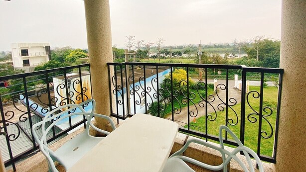 A balcony with a table and chairs, overlooking a green landscape and a distant building. - Isaalice Slip and Slide B&B (Wujie)