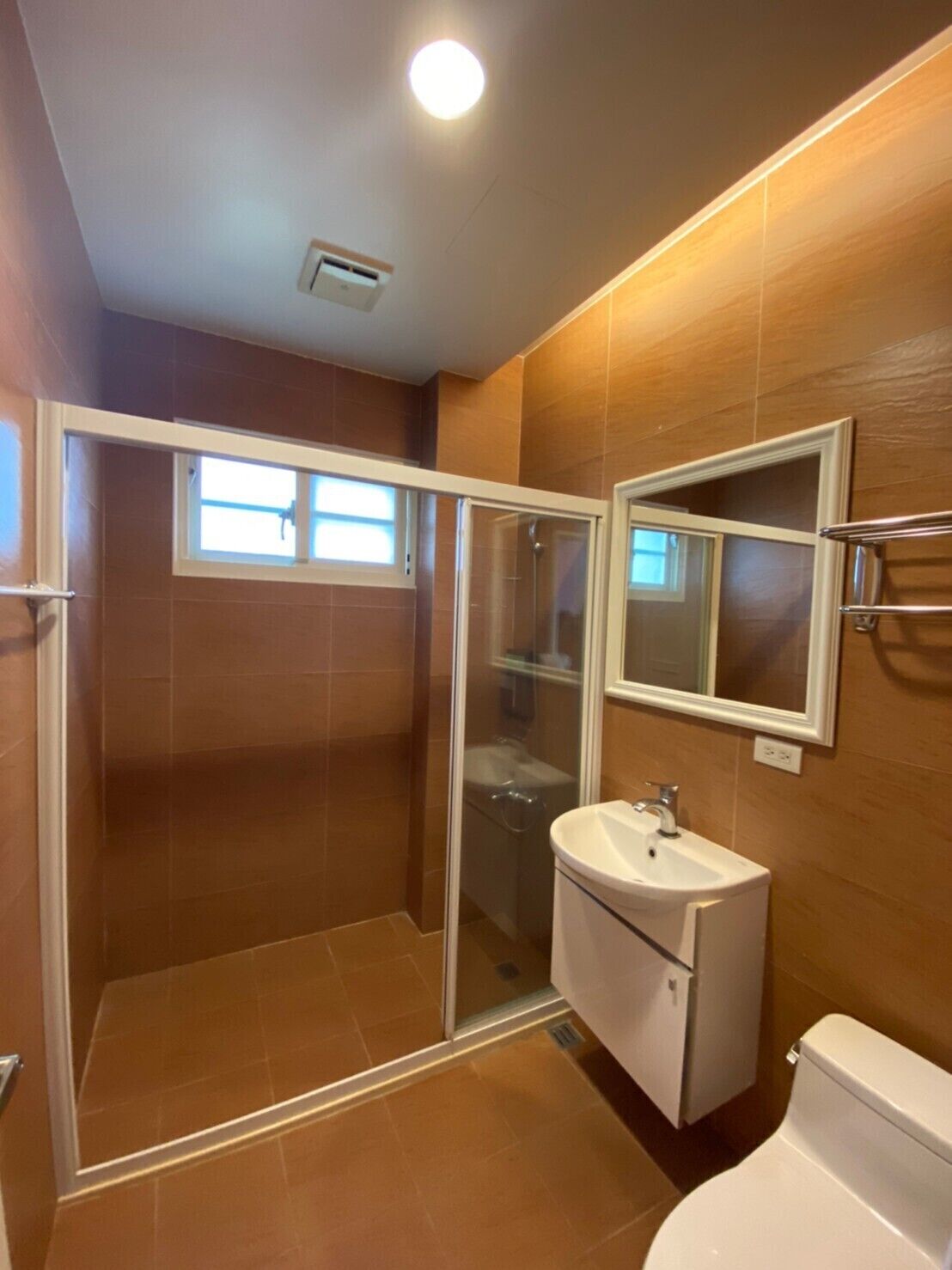 A bathroom with a glass-enclosed shower, a sink, and a toilet.