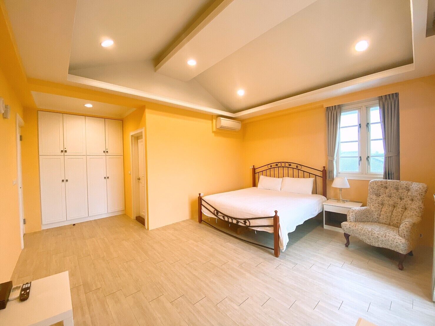 A bedroom with a bed, a chair, a desk, and a wardrobe.
