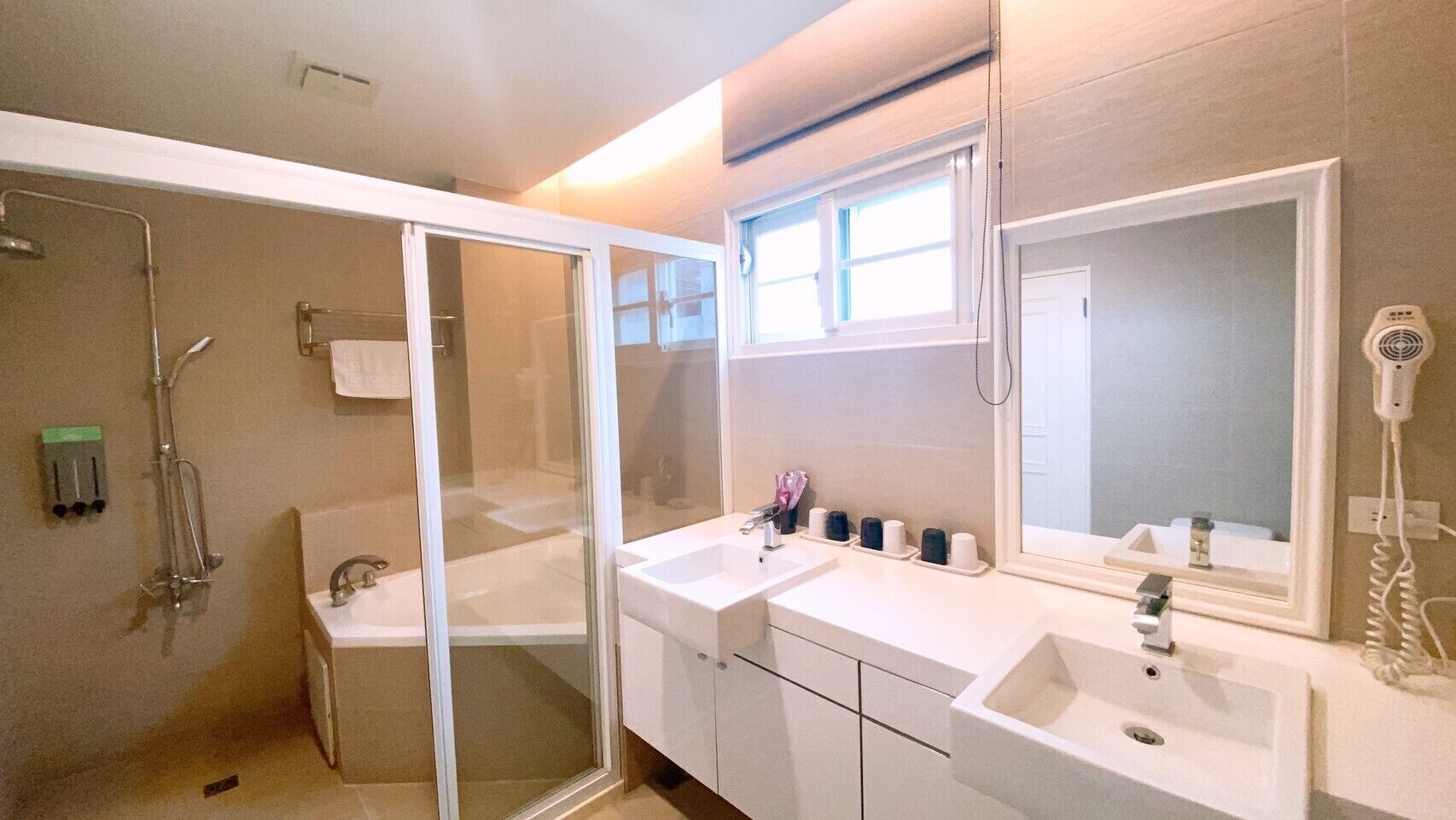 A bathroom with a glass-enclosed shower, a double sink vanity, and a large mirror.