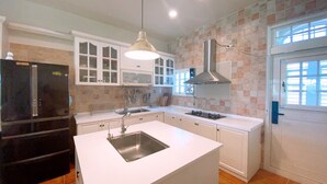 A modern kitchen with white cabinetry, a black refrigerator, a stainless steel sink, and a gas stove. - Isaalice Slip and Slide B&B (Wujie)