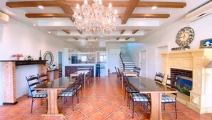 A spacious dining area with a long table and chairs, a fireplace, and a chandelier. - Isaalice Slip and Slide B&B (Wujie)