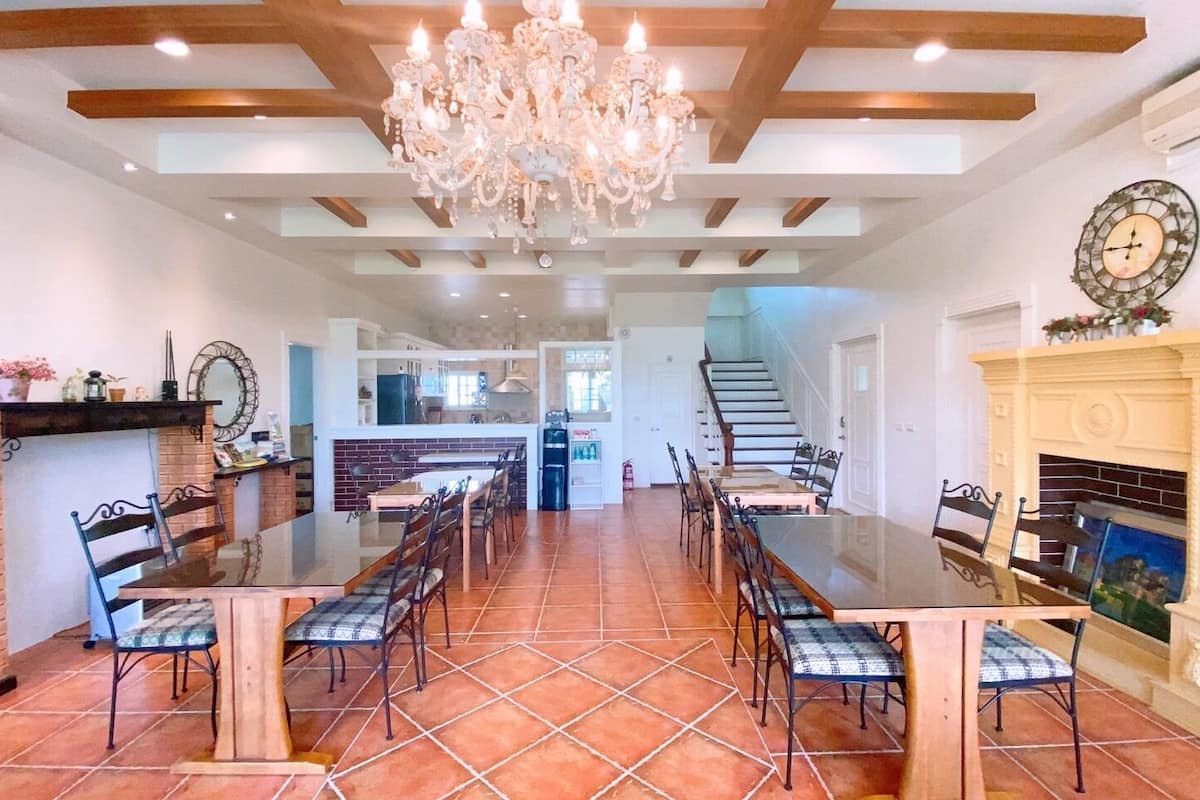 A spacious dining area with a long table and chairs, a fireplace, and a chandelier.