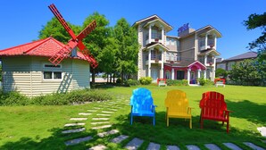 A large house with a windmill, three colorful Adirondack chairs, and a well-maintained lawn. - Isaalice Slip and Slide B&B (Wujie)