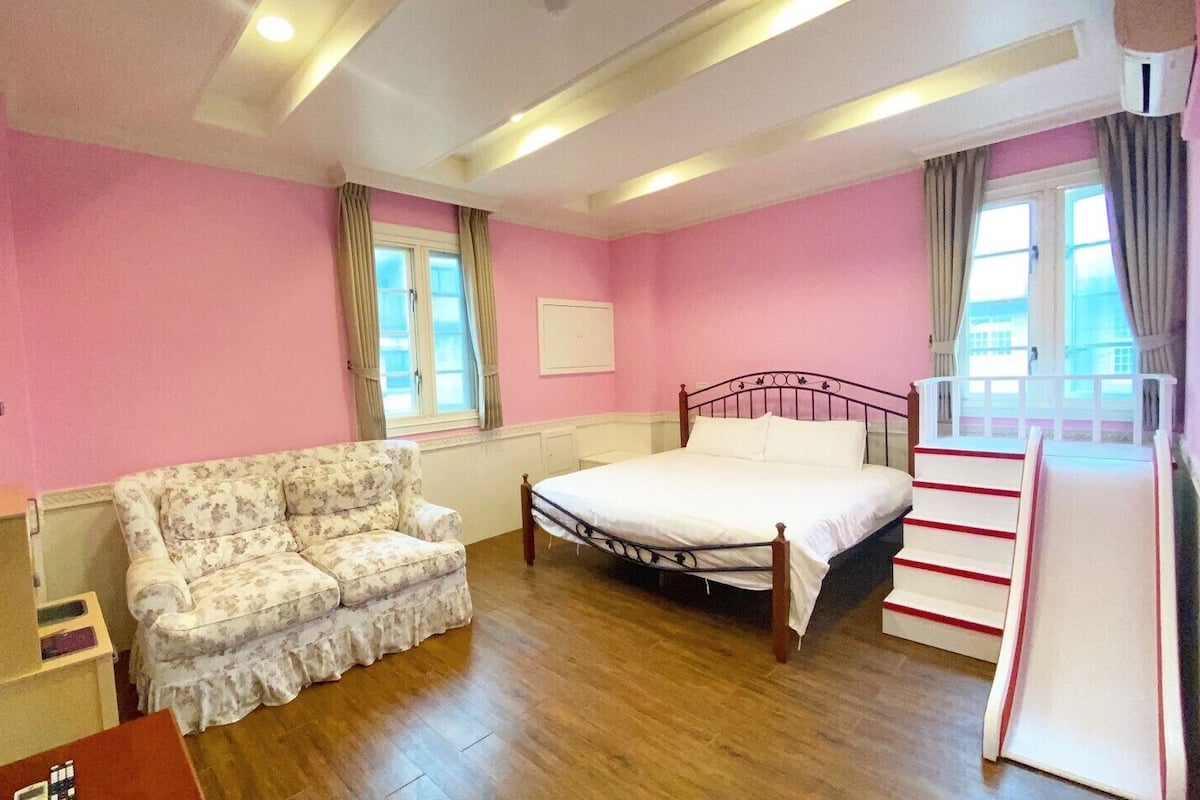 A bedroom with a bed, a sofa, a dresser, and a window.