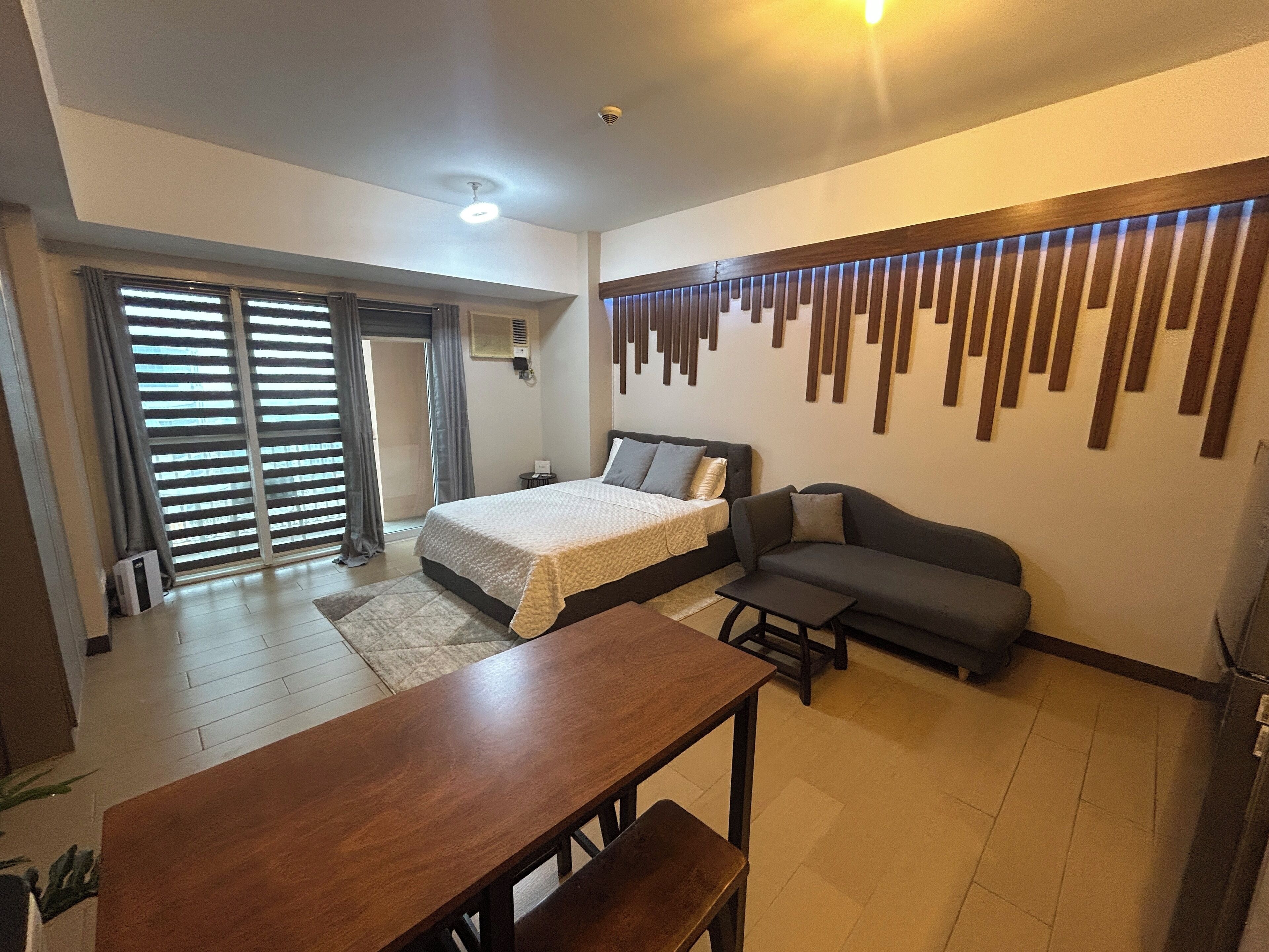 A modern bedroom with a bed, sofa, and a dining table.
