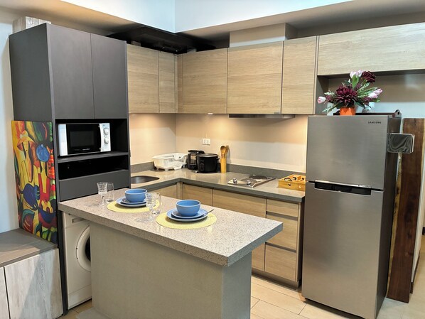 A modern kitchen with a central island, built-in appliances, and wooden cabinetry. - Fantastic Step to the Venice (Taguig)